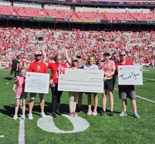 Megan Camp, a Red Cross Board Member, accepted a check at the Nebraska Husker game from UNL's T-Shirt campaign, which will go to the Red Cross in their efforts to help those affected by tornadoes. 